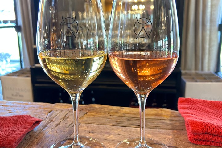 Two wine glasses, one with white wine and one with rosé, on a wooden table.