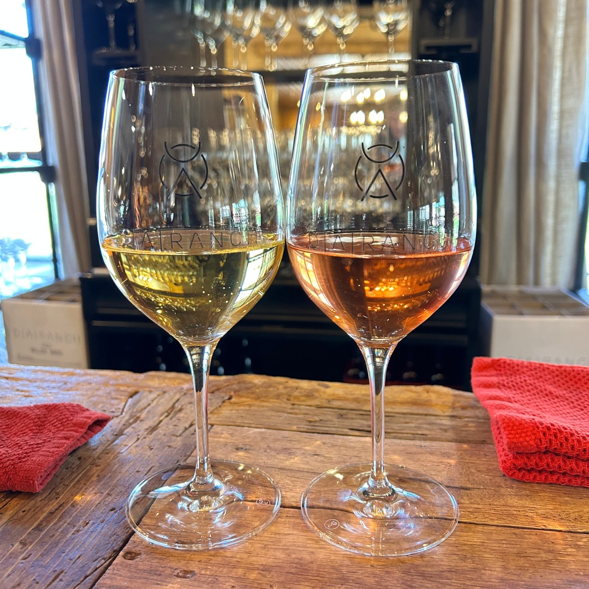 Two wine glasses, one with white wine and one with rosé, on a wooden table.