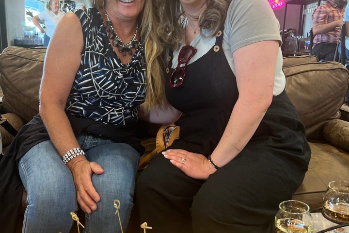 Two people smiling in a restaurant with a charcuterie board in the foreground.