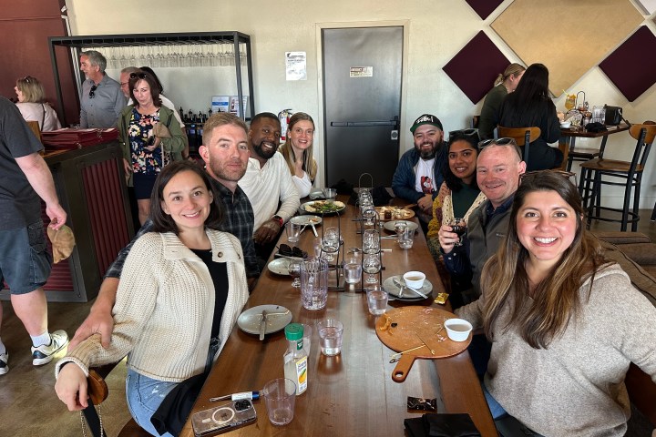 Group of people smiling at a restaurant table with empty dishes.