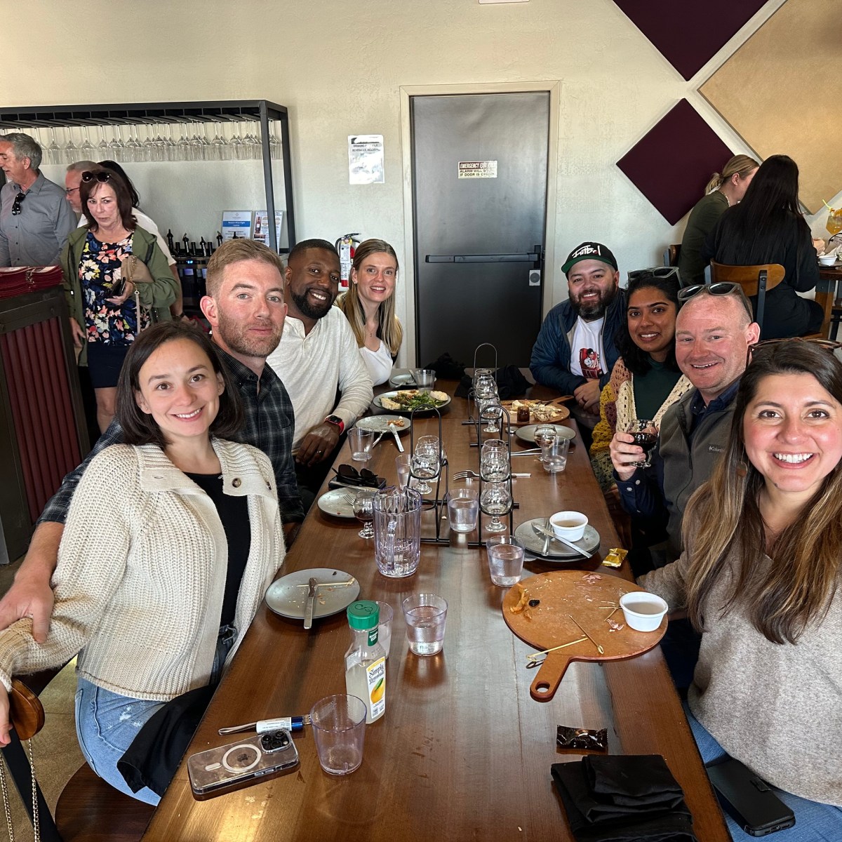 Group of people smiling at a restaurant table with empty dishes.