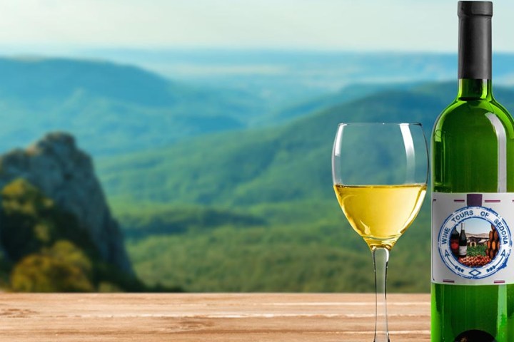 Wine bottle and glass on table with scenic mountain background.