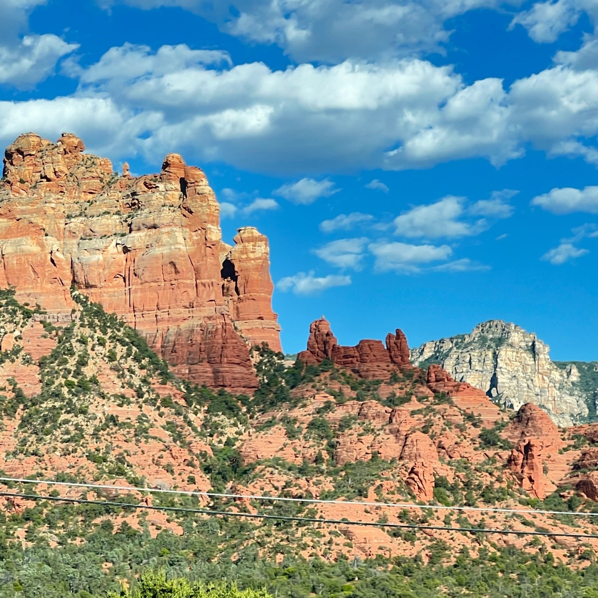 Red rock formations under a blue sky with scattered clouds.