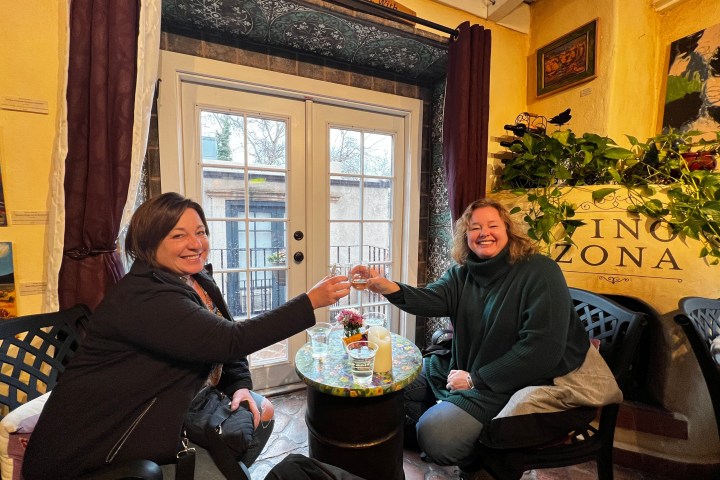 Two people clinking glasses at a small table in a cozy indoor setting.