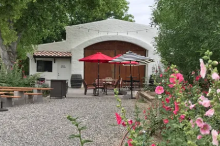 Outdoor patio with colorful umbrellas, wooden benches, and blooming flowers.