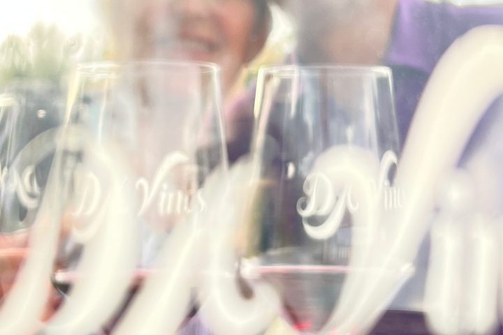 Blurry reflection of two people through wine glasses with text in focus.