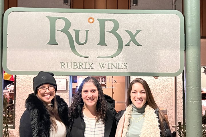 Three people smiling under a sign that reads 'RuBx Rubrix Wines'.