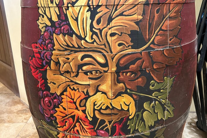 Painted barrel with leafy face design in vibrant autumn colors.