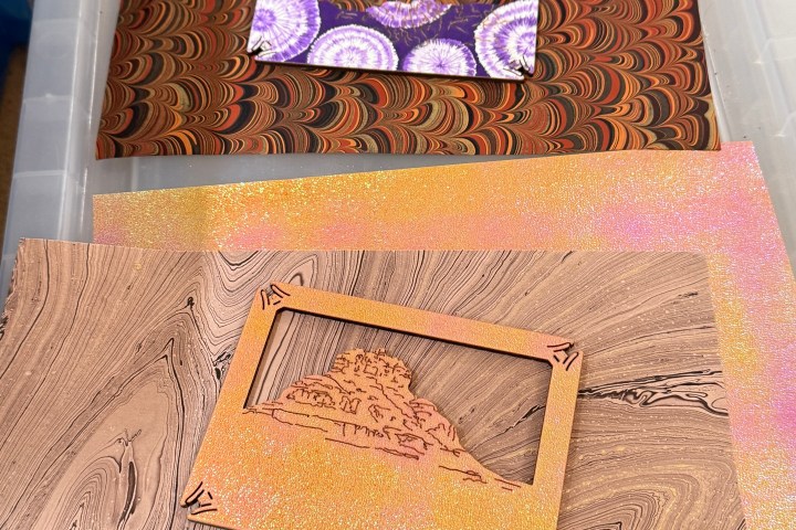 Decorative marbled paper and a cutout frame on a plastic bin lid.