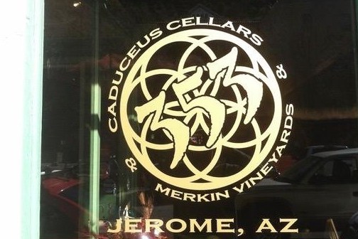 Logo of Caduceus Cellars on a window in Jerome, AZ, with geometric design.