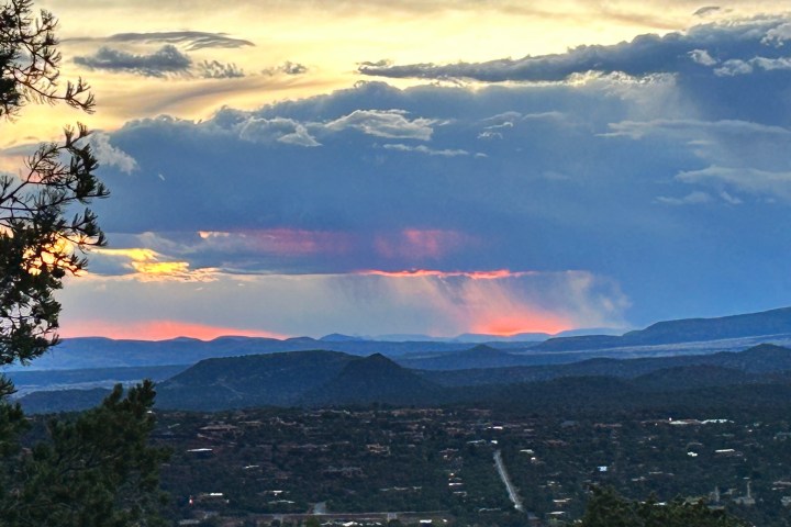 Landscape view of distant mountains, colorful sunset, and dramatic clouds.