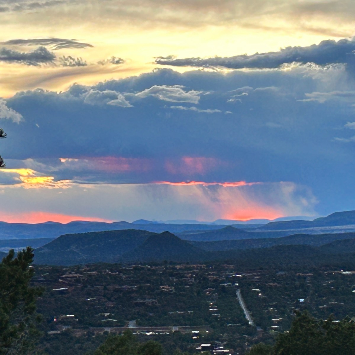 Landscape view of distant mountains, colorful sunset, and dramatic clouds.