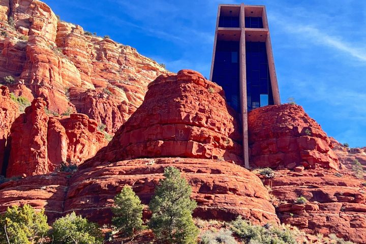 Modern building atop red rock formations under a clear blue sky.