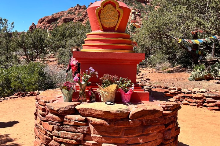 Colorful stupa monument on a stone base surrounded by desert landscape with clear blue sky.