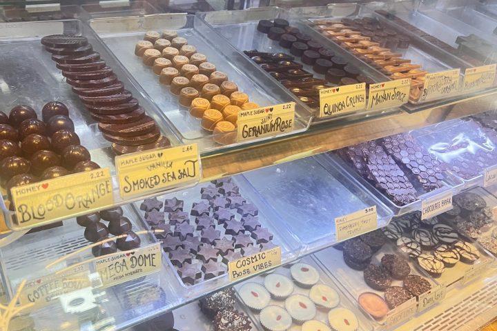 Display case with various chocolates, each labeled with handwritten tags.