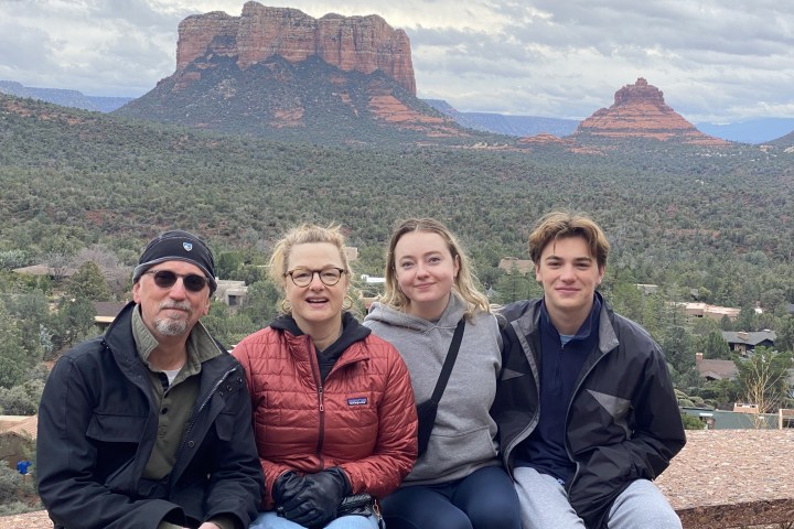 Four people posing with red rock formations in the background on a cloudy day.
