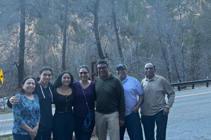Group of people posing on a road with a forested mountain background.