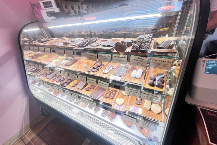 Display case with assorted chocolates and truffles on wooden trays in a shop.
