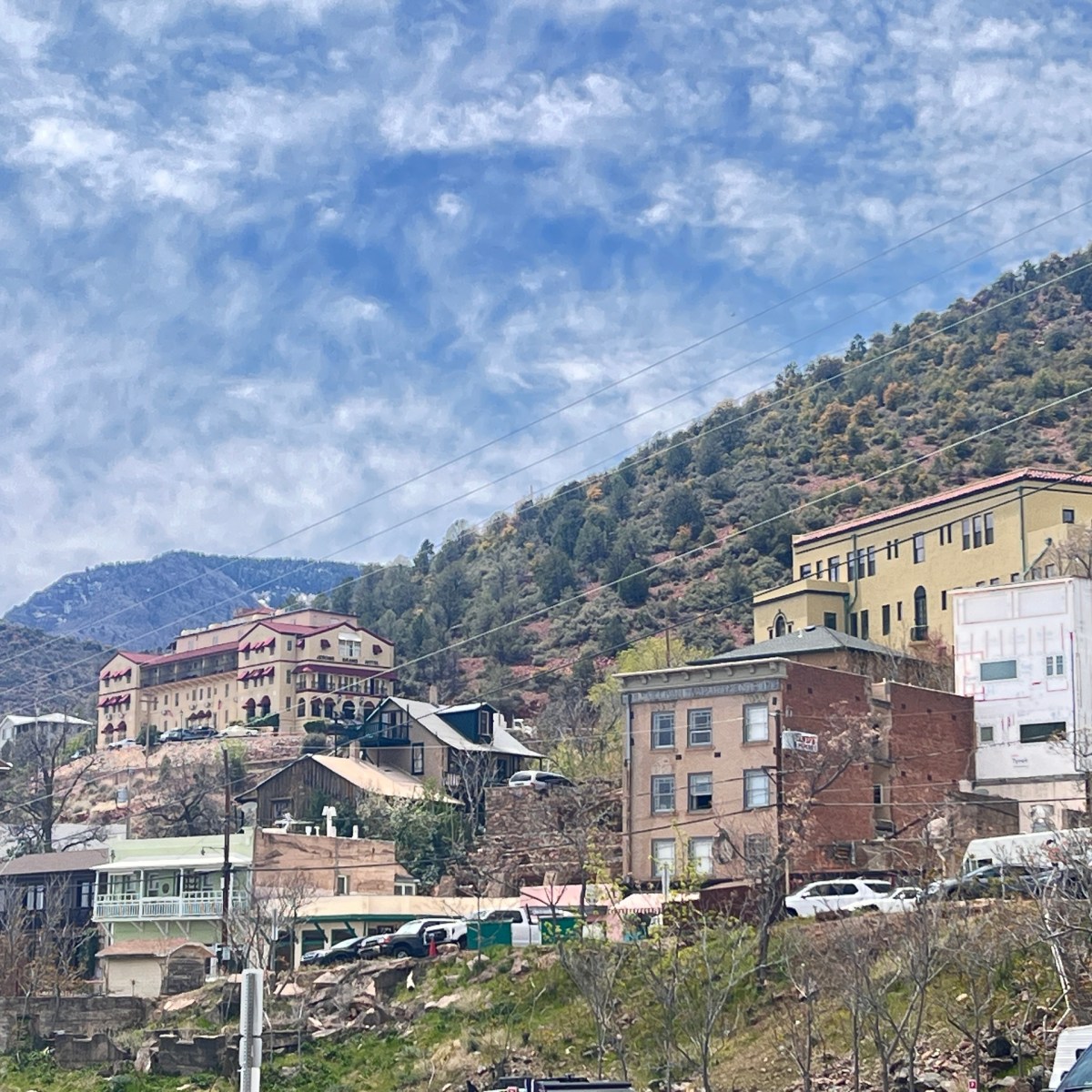 Hillside town with colorful buildings and a mountainous backdrop under a blue sky.