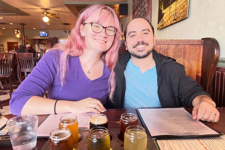 Two people smiling at a restaurant table with drinks and menus.
