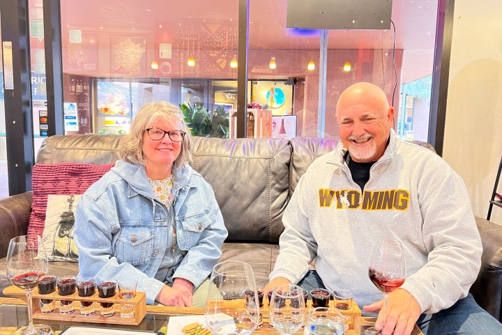 Two people sitting on a couch, enjoying wine samples in a cozy setting.