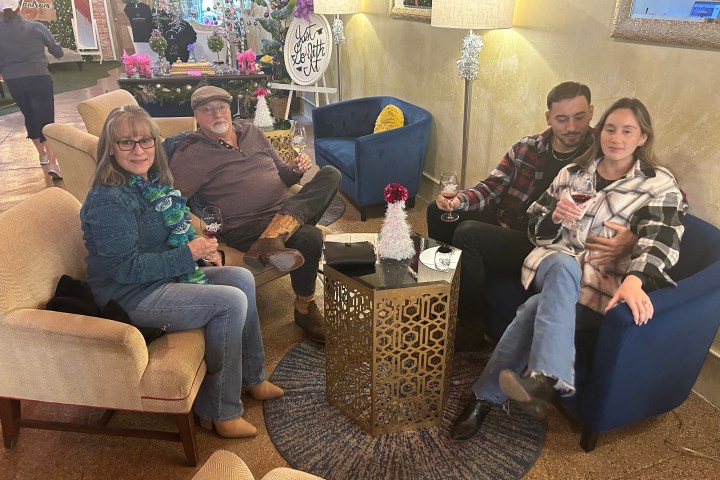 Four people sitting in a cozy lounge area, enjoying drinks near a festive decoration.