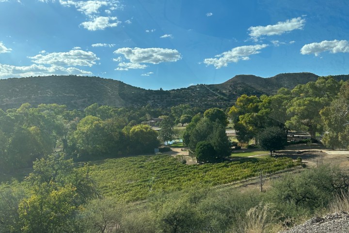 Landscape with green fields, trees, hills, and blue sky with clouds.