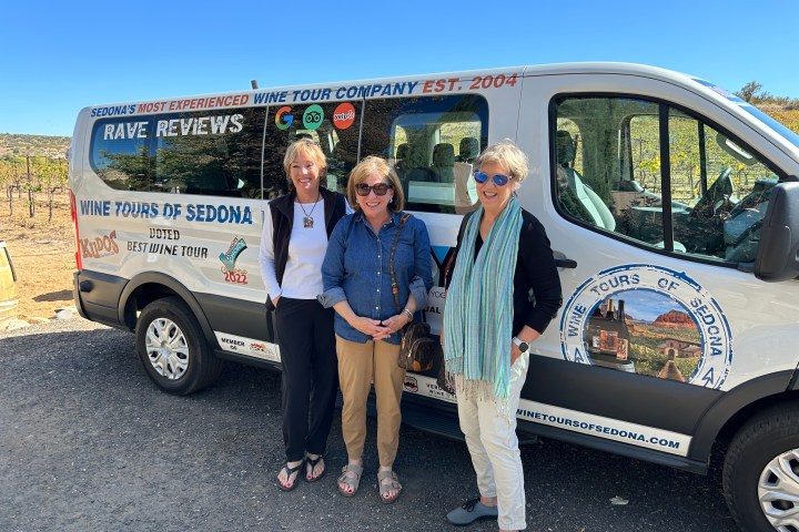 Three women standing in front of a Wine Tours of Sedona van.