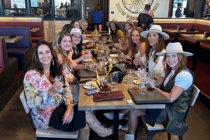 Group of women with hats enjoying drinks at a restaurant table indoors.