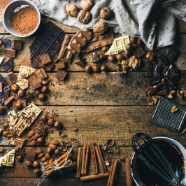 Assorted chocolates, nuts, and baking ingredients on a wooden table.