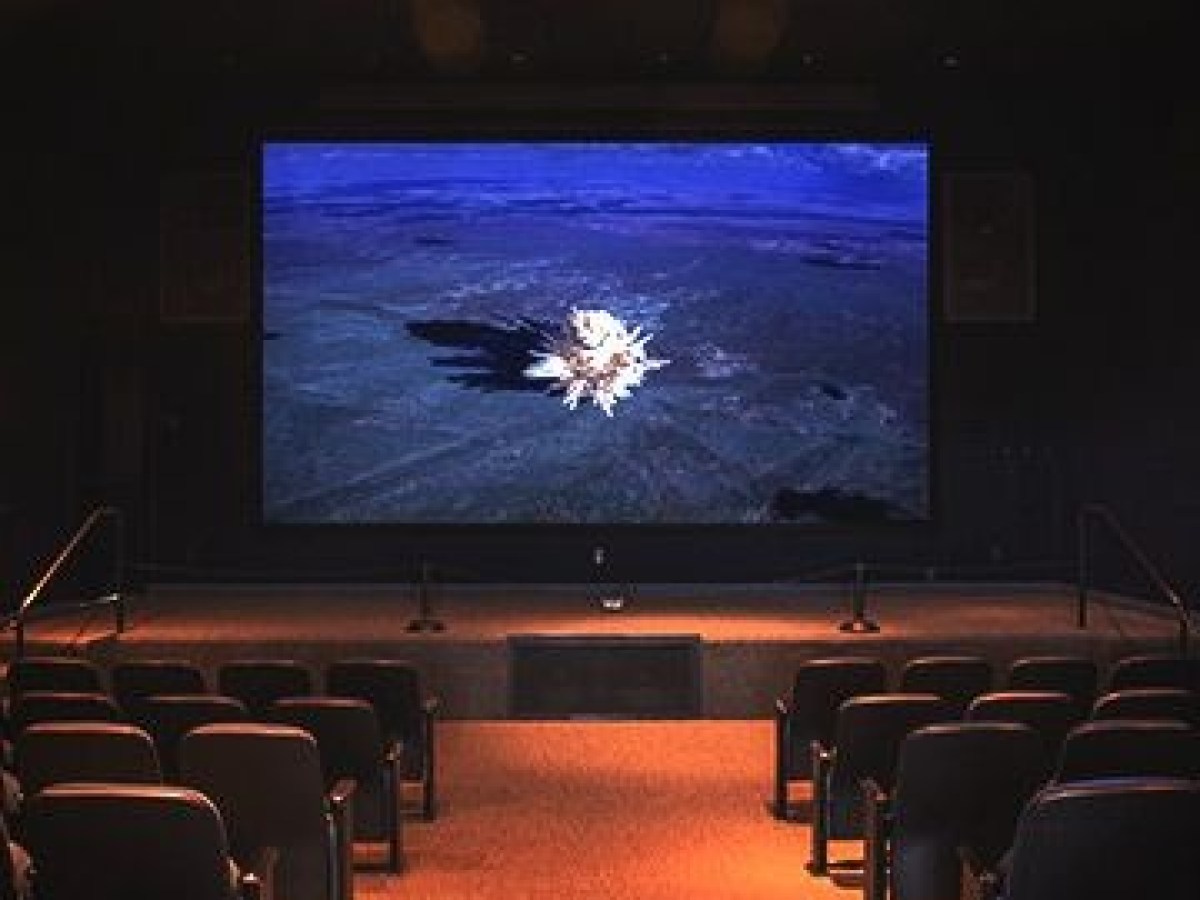 Empty theater with screen showing a nature scene and rows of seats.