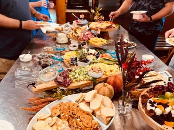 People at a buffet table with assorted food and snacks in a kitchen setting.