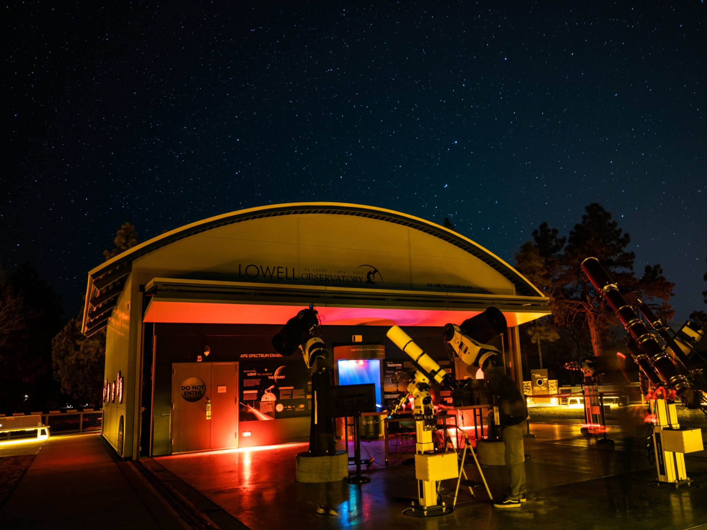 Night view of Lowell Observatory with telescopes and starry sky in the background.