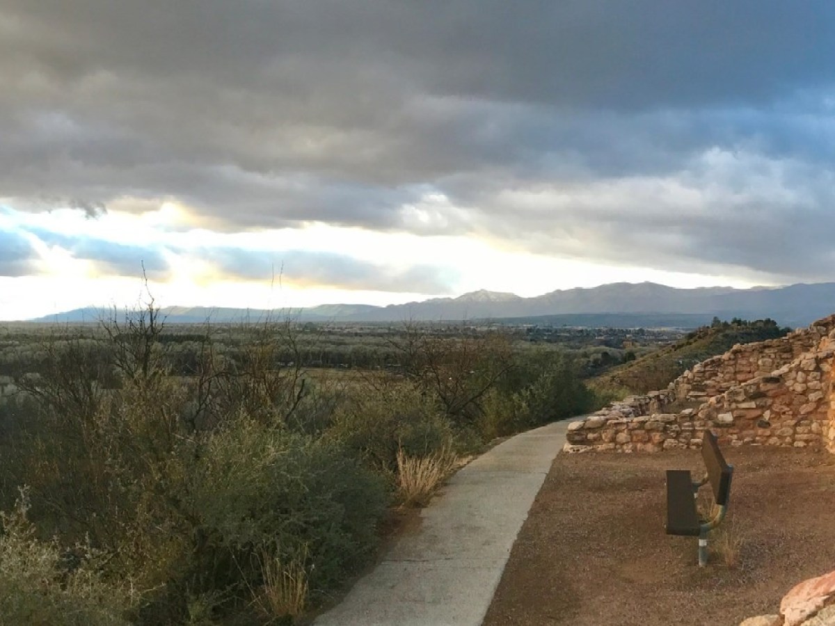 Panoramic view of ancient stone ruins against a cloudy sky and distant landscape at sunset.