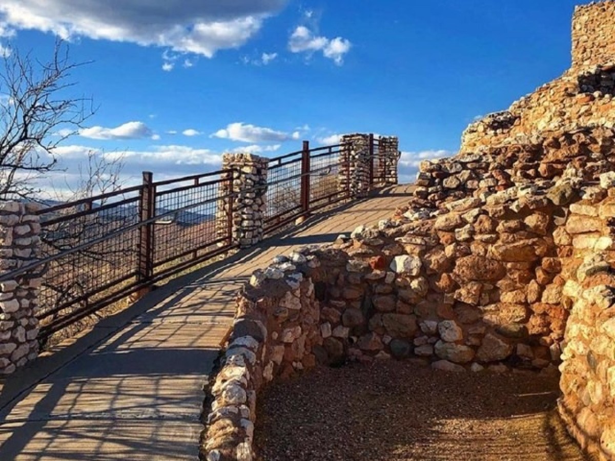 Stone pathway with railing, blue sky, and scattered clouds.
