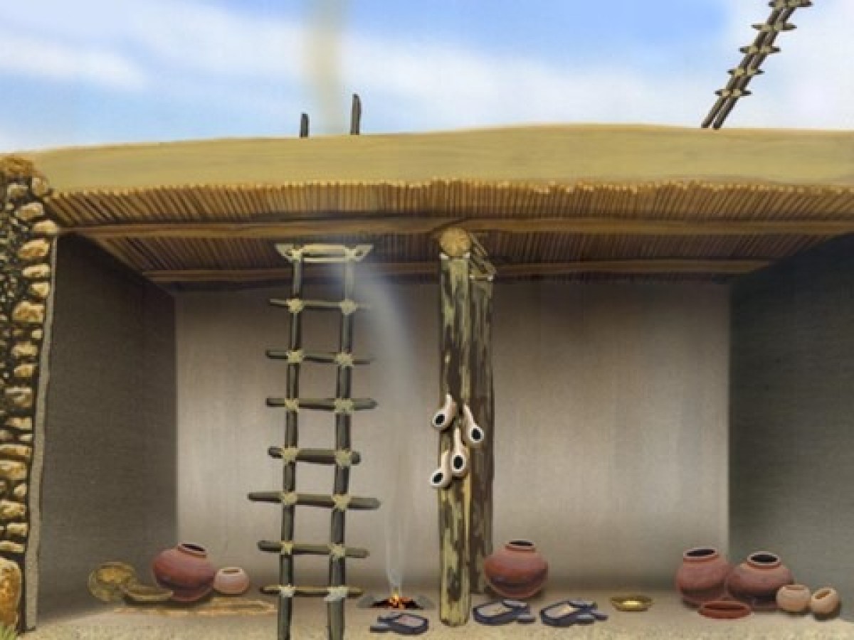 Ancient dwelling with stone walls, ladders, pottery, and a central wooden post under a thatched roof.