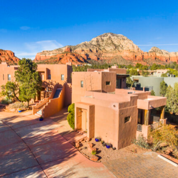 Adobe-style house with red rock mountain in the background, clear blue sky.