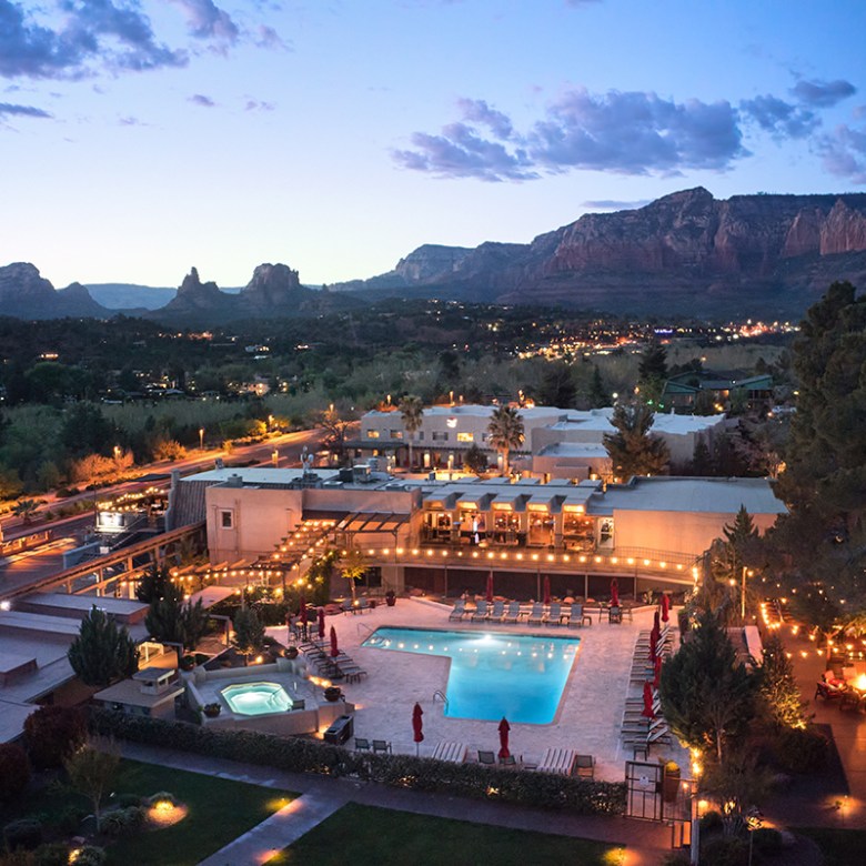 Aerial view of pool and spa area at dusk, with mountains in the background.