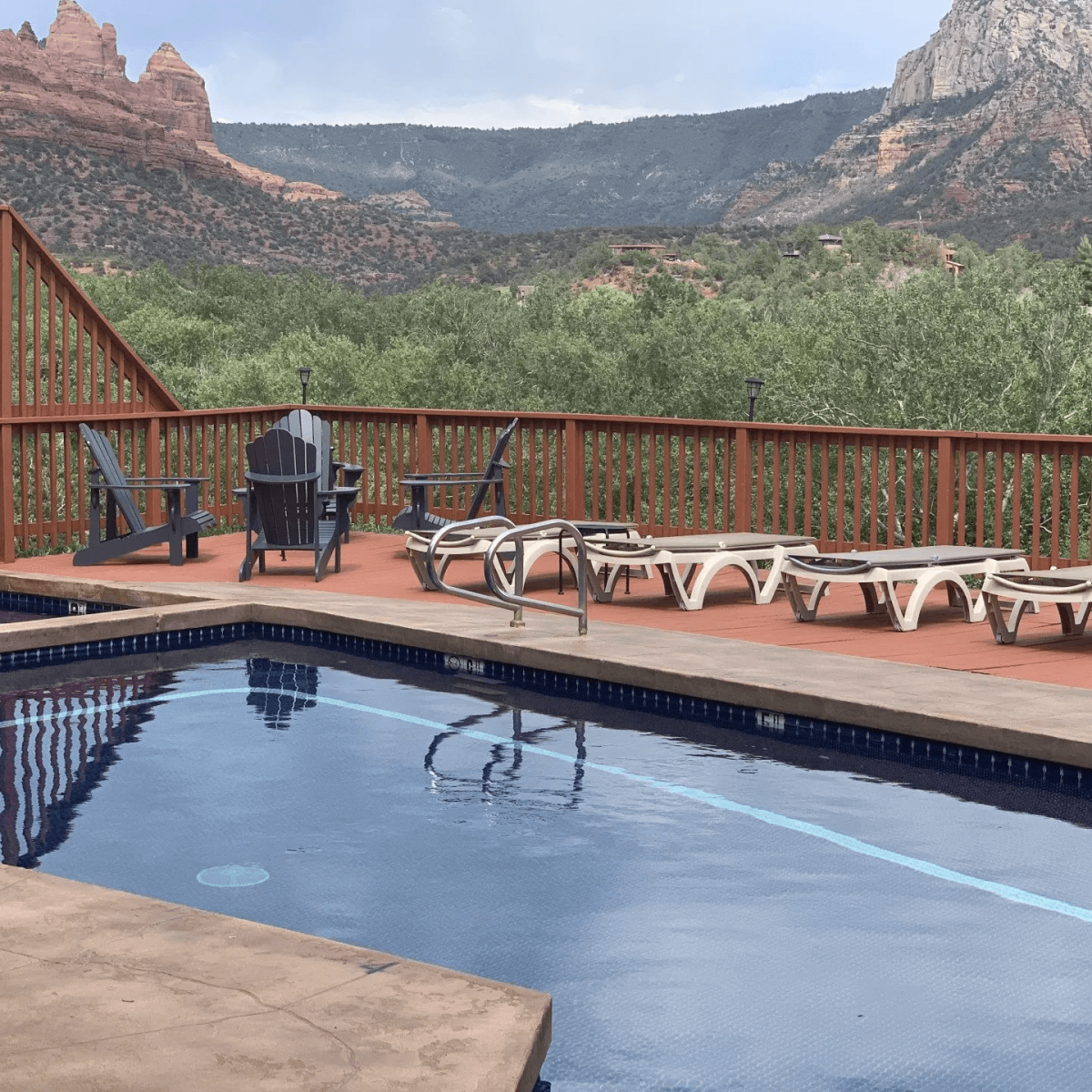 Swimming pool with lounge chairs and red rock mountains in the background.