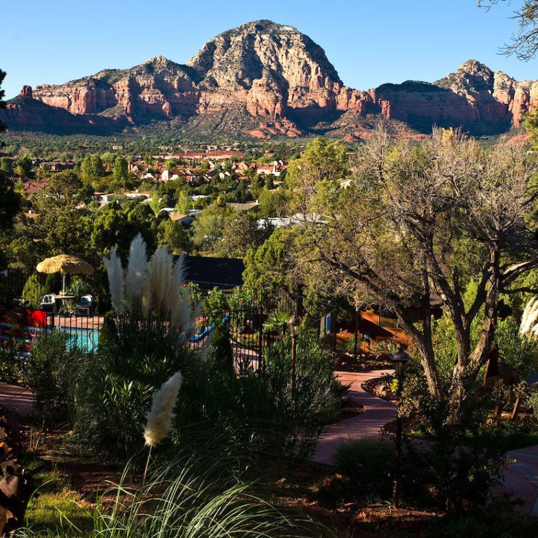 View of Sedona red rock formations with trees and houses in foreground.