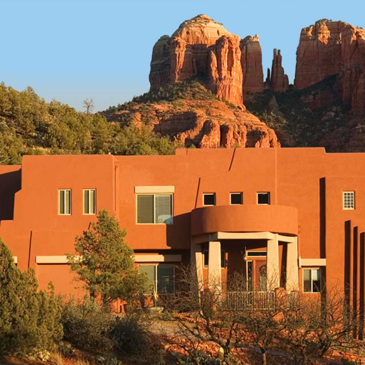 Modern adobe home with red rock mountains in the background.