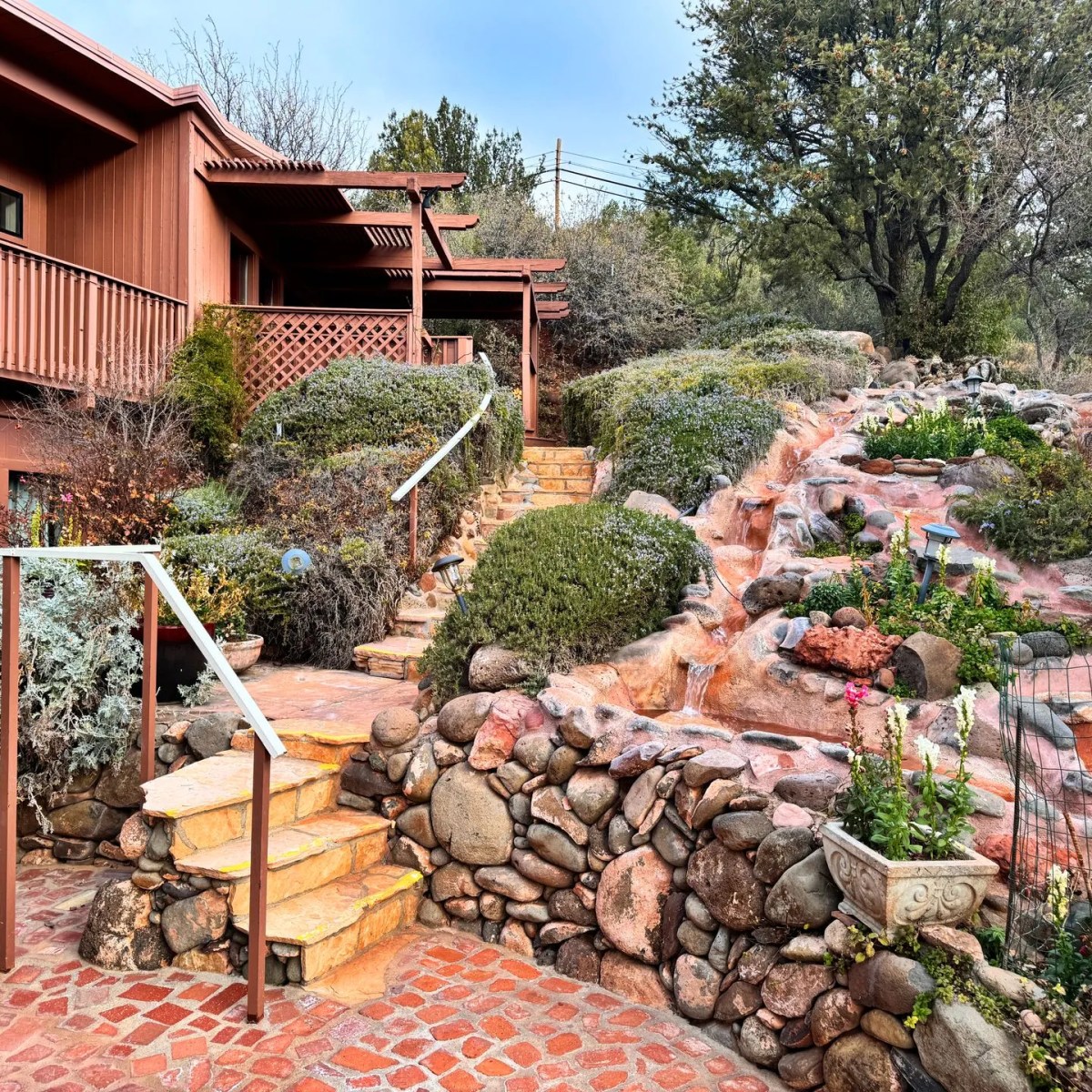 A house with stone stairs, rock wall, and landscaped waterfall garden.