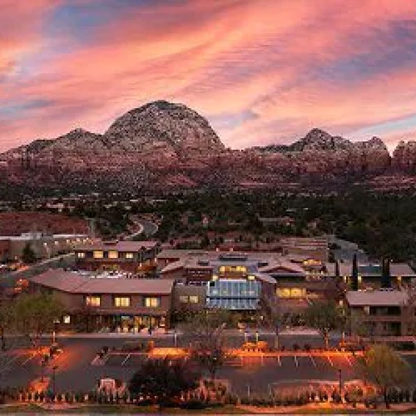 Mountain view at sunset with pink clouds and a building in foreground.